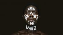 A Black man;s face with the words— Les Blancs The Whites— witten on his face in white paint.